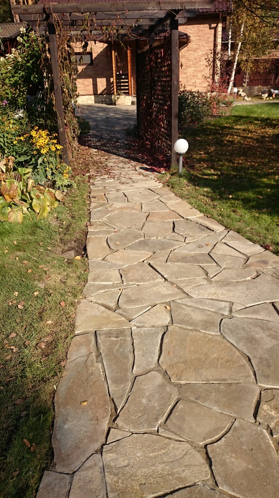 Элемент главной дорожки из натурального камня и деревянная пергола с виноградом