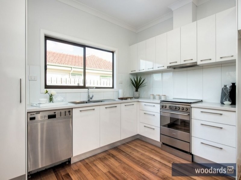 Photo of a small contemporary l-shaped eat-in kitchen in Melbourne with a double-bowl sink, raised-panel cabinets, white cabinets, laminate benchtops, white splashback, ceramic splashback, stainless steel appliances and light hardwood floors.