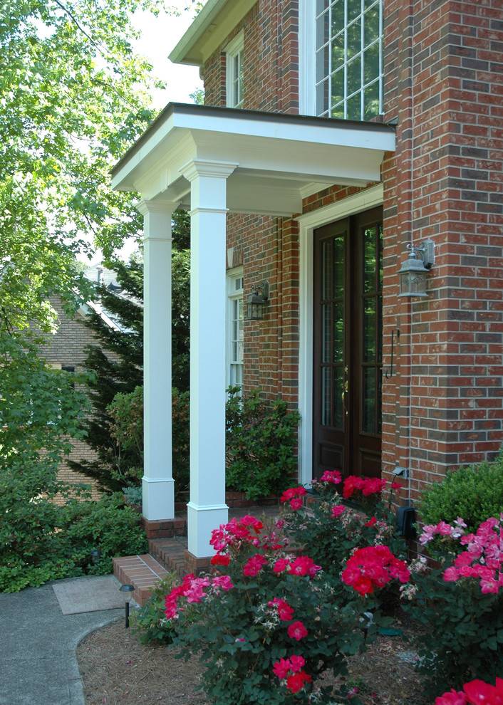 Photo of a mid-sized traditional front yard verandah in Atlanta with brick pavers and a roof extension.
