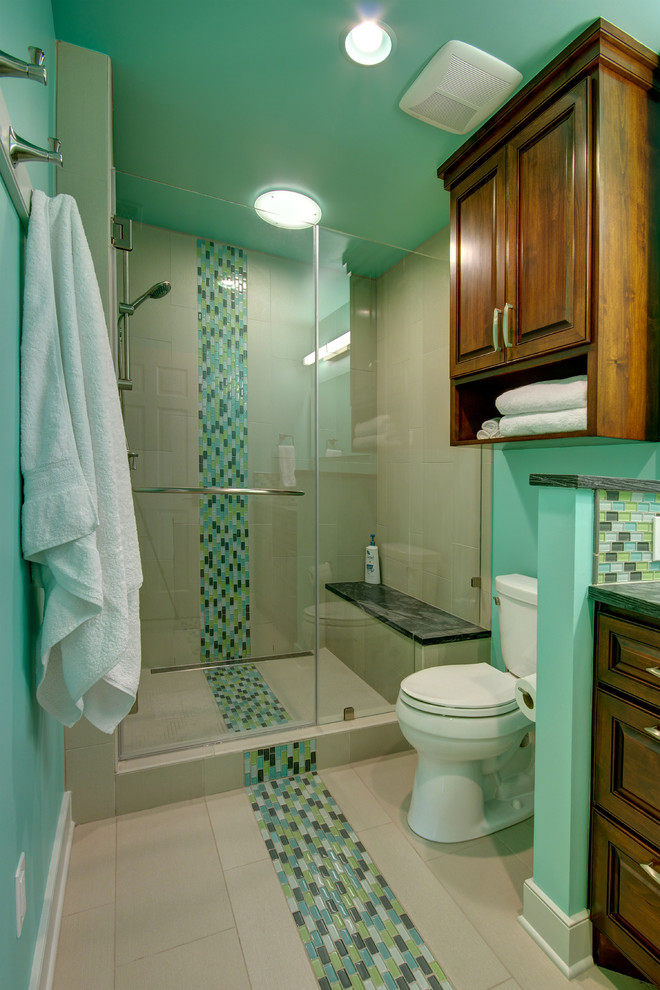 Photo of a mid-sized traditional bathroom in Austin with raised-panel cabinets, medium wood cabinets, an alcove shower, a two-piece toilet, multi-coloured tile, mosaic tile, green walls, soapstone benchtops and porcelain floors.