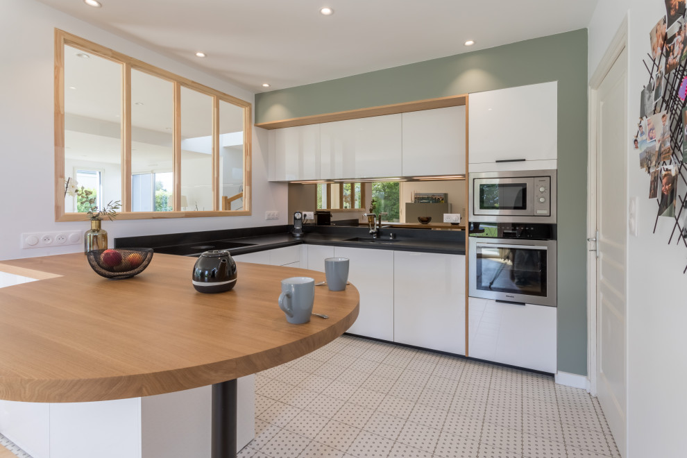 Design ideas for a small modern u-shaped open plan kitchen in Other with an integrated sink, flat-panel cabinets, white cabinets, granite worktops, mirror splashback, stainless steel appliances, cement flooring, a breakfast bar, grey floors and black worktops.