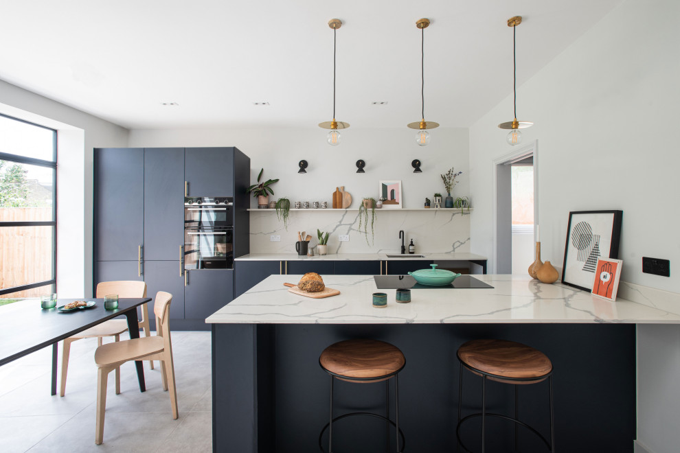 Large contemporary kitchen/diner in London with a submerged sink, flat-panel cabinets, blue cabinets, quartz worktops, marble splashback, integrated appliances, concrete flooring, an island and grey floors.