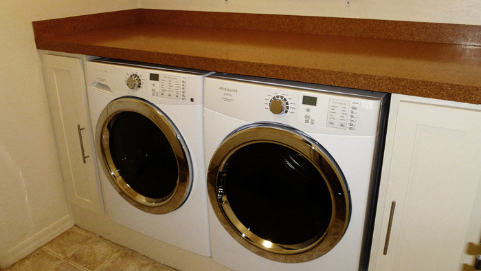 Photo of a small contemporary single-wall dedicated laundry room in Phoenix with white cabinets, solid surface benchtops, white walls, ceramic floors and a side-by-side washer and dryer.