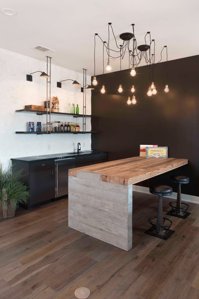 Country seated home bar in Austin with black cabinets, wood benchtops, light hardwood floors, brown floor, brown benchtop and flat-panel cabinets.