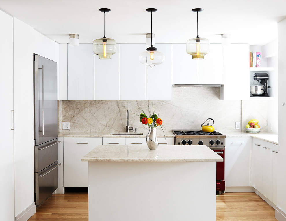 Photo of a mid-sized modern u-shaped open plan kitchen in New York with an undermount sink, glass-front cabinets, white cabinets, marble benchtops, white splashback, stone slab splashback, coloured appliances, light hardwood floors and with island.