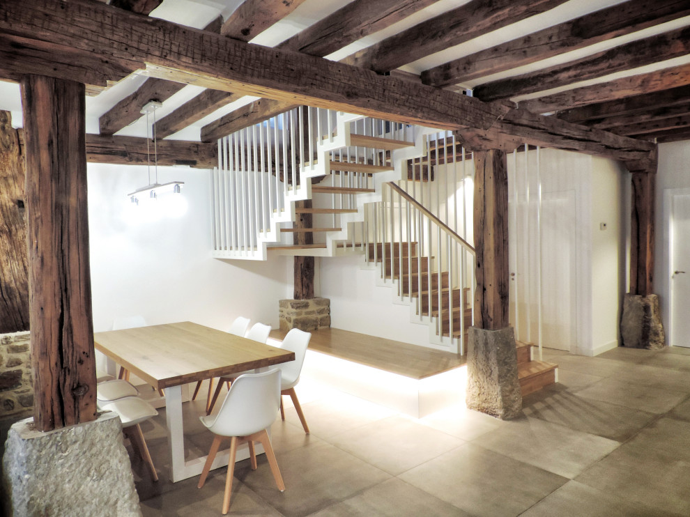 Diseño de comedor de cocina rural grande con paredes blancas, suelo de baldosas de porcelana, chimenea de esquina, suelo gris y madera