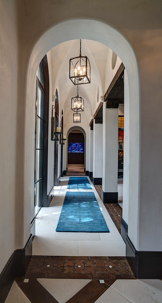 This is an example of a traditional hallway in Houston with white walls and travertine floors.