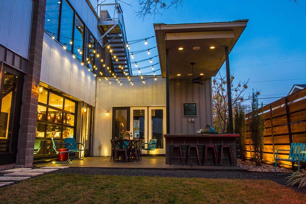 Inspiration for a mid-sized industrial backyard patio in Austin with an outdoor kitchen, concrete slab and a roof extension.