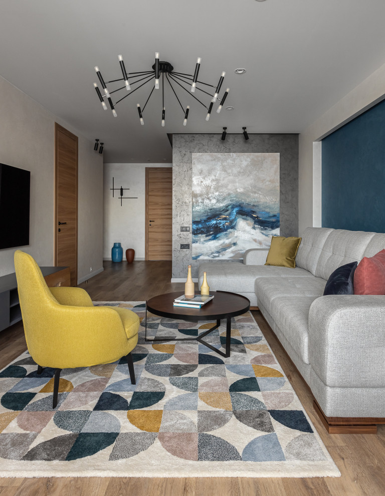 Стильный дизайн: открытая, серо-белая гостиная комната среднего размера в современном стиле с синими стенами, светлым паркетным полом, телевизором на стене, коричневым полом и акцентной стеной - последний тренд