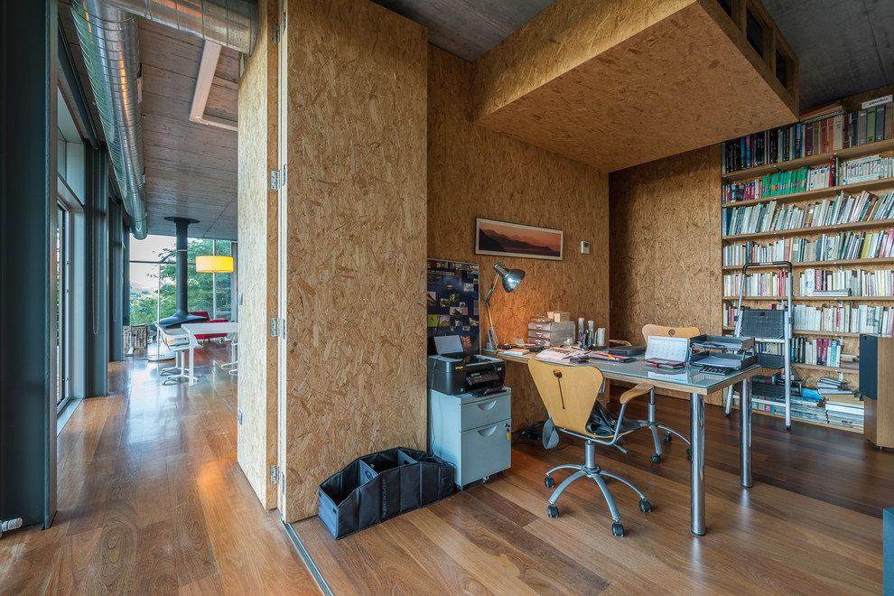 Mid-sized industrial study room in Other with brown walls, medium hardwood floors, no fireplace and a built-in desk.