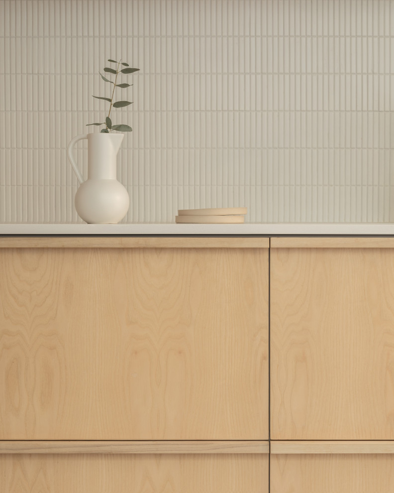 This is an example of a medium sized scandinavian grey and white galley kitchen/diner in London with an integrated sink, flat-panel cabinets, light wood cabinets, composite countertops, white splashback, metro tiled splashback, stainless steel appliances, concrete flooring, an island, grey floors, white worktops and exposed beams.