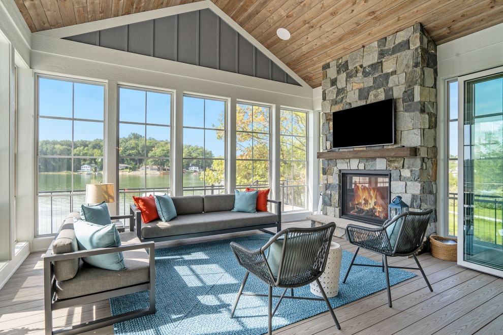 Photo of a country sunroom in Grand Rapids with medium hardwood floors, a standard fireplace, a stone fireplace surround, a standard ceiling and brown floor.