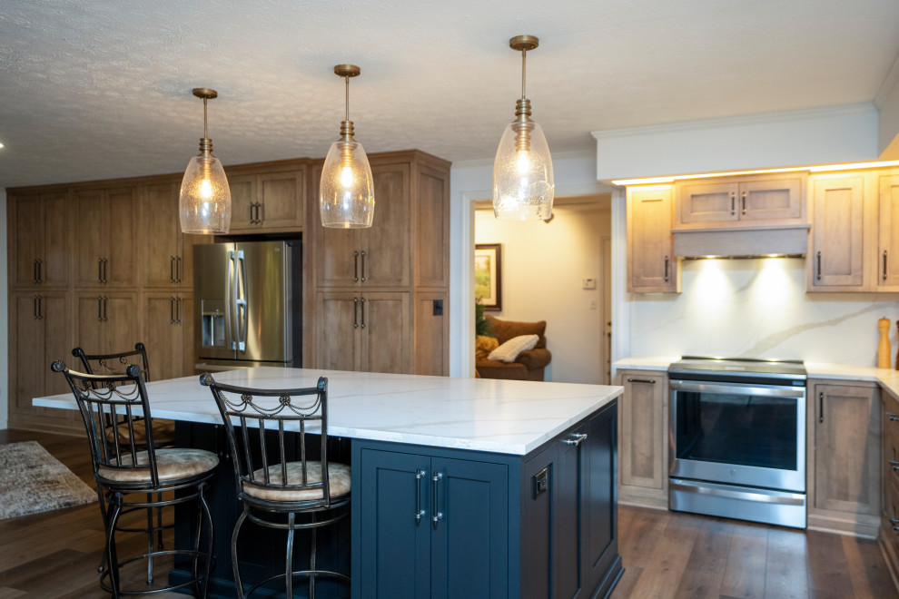 Inspiration for a large transitional l-shaped medium tone wood floor and brown floor eat-in kitchen remodel with a single-bowl sink, shaker cabinets, medium tone wood cabinets, quartz countertops, white backsplash, quartz backsplash, stainless steel appliances, an island and white countertops