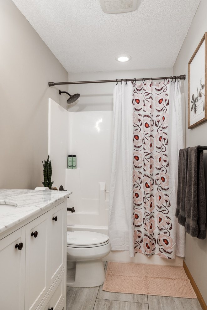 Medium sized shower room bathroom in Minneapolis with shaker cabinets, white cabinets, an alcove bath, a shower/bath combination, a two-piece toilet, beige walls, a built-in sink, engineered stone worktops, beige floors, a shower curtain, white worktops, a single sink and a freestanding vanity unit.