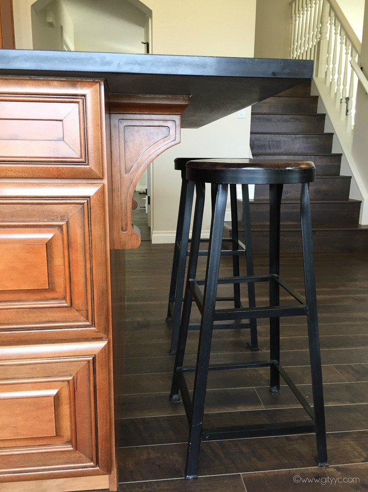 Eat-in kitchen - mid-sized rustic l-shaped laminate floor and black floor eat-in kitchen idea in Calgary with a drop-in sink, raised-panel cabinets, medium tone wood cabinets, quartzite countertops, white backsplash, ceramic backsplash, stainless steel appliances and an island