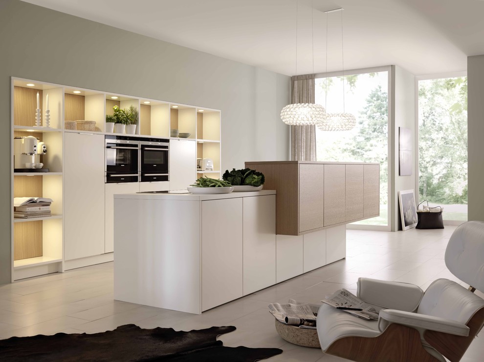 Design ideas for a mid-sized modern open plan kitchen in Stuttgart with flat-panel cabinets, light hardwood floors, with island and black appliances.