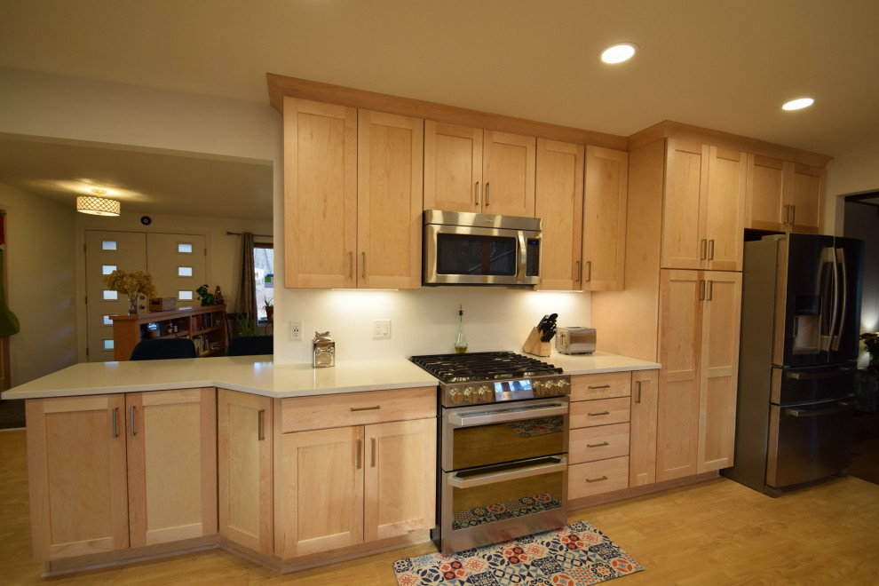 Kitchen - galley vinyl floor kitchen idea with an undermount sink, shaker cabinets, light wood cabinets, quartz countertops, stainless steel appliances and white countertops