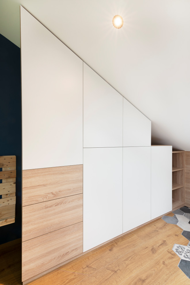 This is an example of a large contemporary gender-neutral built-in wardrobe in Nancy with laminate floors, brown floor, flat-panel cabinets and white cabinets.