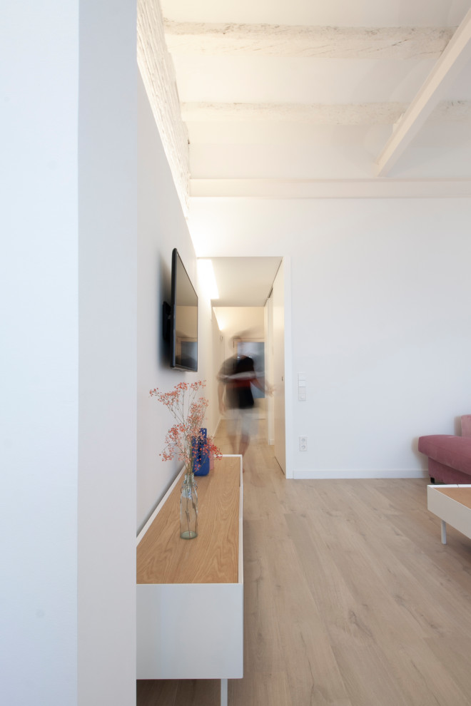 Diseño de recibidores y pasillos abovedados actuales con paredes blancas, suelo laminado, suelo marrón y iluminación