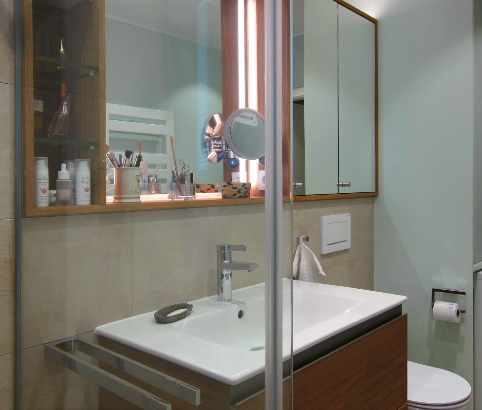 Exempel på ett litet modernt badrum med dusch, med släta luckor, skåp i mellenmörkt trä, en kantlös dusch, en vägghängd toalettstol, beige kakel, keramikplattor, gröna väggar, klinkergolv i porslin, ett fristående handfat, beiget golv och dusch med gångjärnsdörr