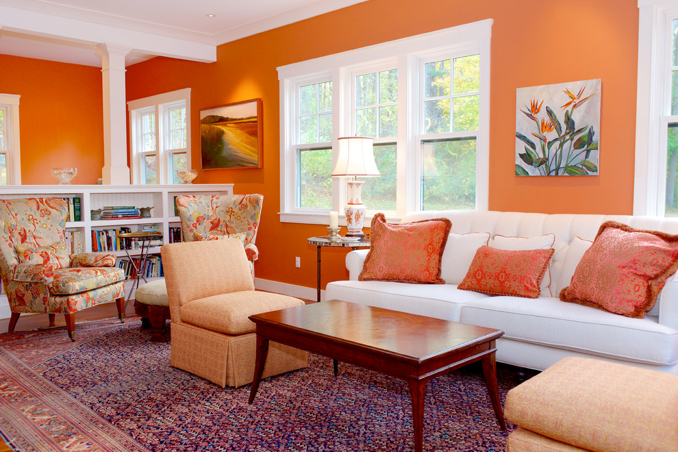 This is an example of a mid-sized transitional formal loft-style living room in Boston with orange walls, light hardwood floors, no fireplace, no tv and beige floor.