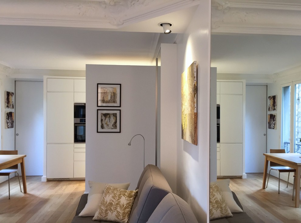 Cette image montre une salle de séjour design de taille moyenne et ouverte avec un mur blanc, parquet clair, aucune cheminée, aucun téléviseur et un sol beige.