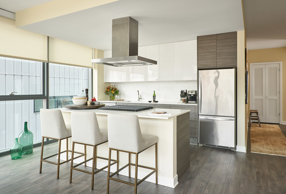 Small contemporary galley kitchen in Chicago with flat-panel cabinets, white cabinets, quartz benchtops, white splashback, with island, brown floor, white benchtop, an undermount sink, stainless steel appliances and dark hardwood floors.