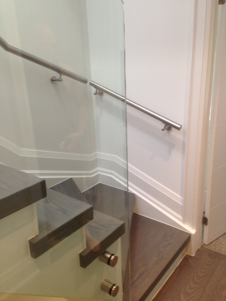 This is an example of a mid-sized modern wood l-shaped staircase in Toronto with glass risers.