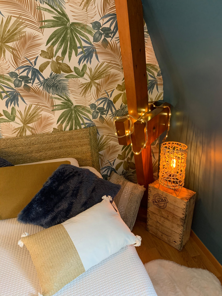 Foto de dormitorio tipo loft tropical de tamaño medio sin chimenea con paredes azules, suelo de madera clara, suelo marrón, vigas vistas y papel pintado