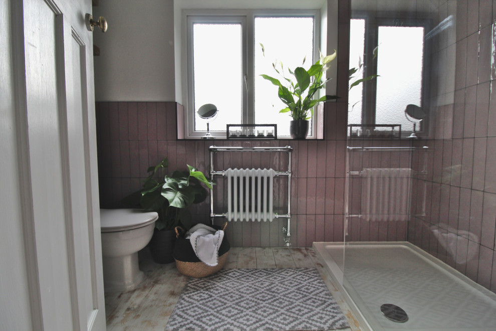 This is an example of a small industrial master bathroom in Cheshire with an open shower, a two-piece toilet, pink tile, ceramic tile, white walls, light hardwood floors, a pedestal sink, white floor and an open shower.