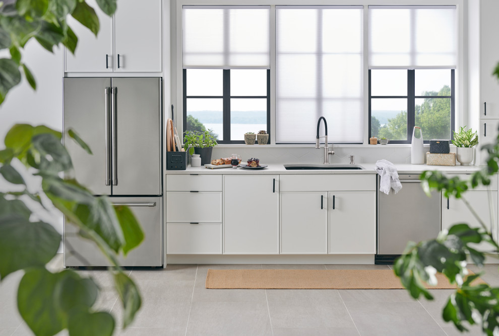 Transitional l-shaped eat-in kitchen with a drop-in sink, shaker cabinets, white cabinets, white splashback, stainless steel appliances, with island, grey floor and grey benchtop.