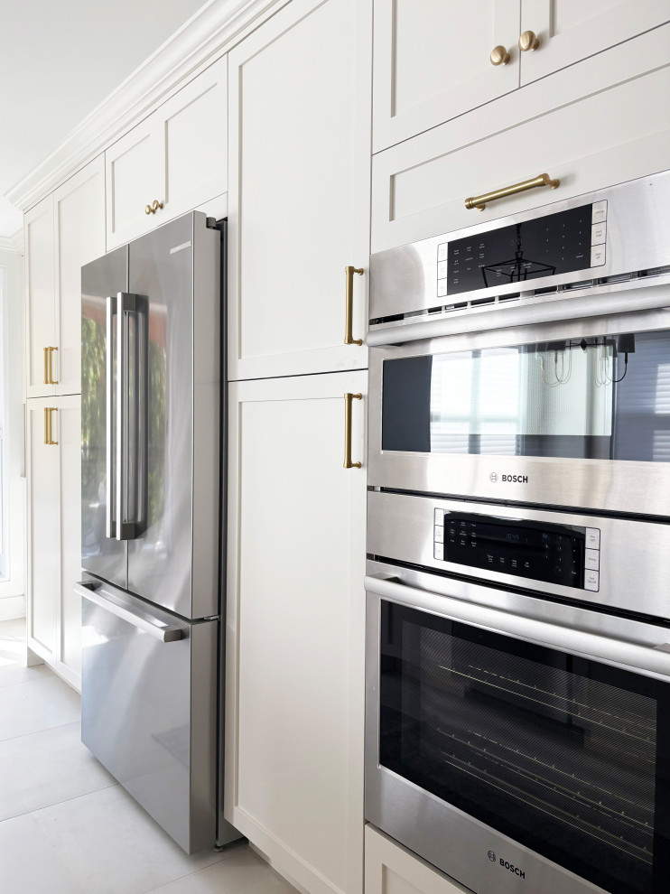 Example of a transitional galley porcelain tile and white floor eat-in kitchen design in Ottawa with an undermount sink, shaker cabinets, white cabinets, quartz countertops, white backsplash, quartz backsplash, stainless steel appliances, a peninsula and white countertops