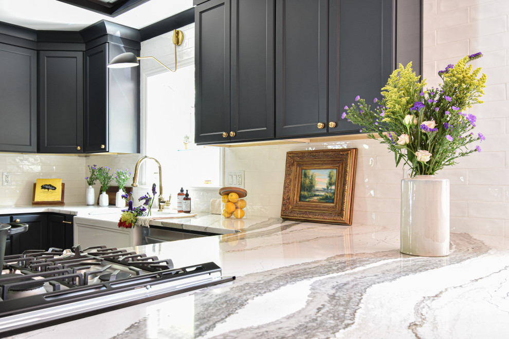 Mid-sized transitional u-shaped laminate floor open concept kitchen photo with a farmhouse sink, black cabinets, quartzite countertops, white backsplash and a peninsula