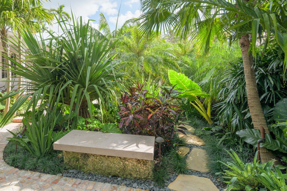 This is an example of a mid-sized tropical full sun garden in Miami with brick pavers.