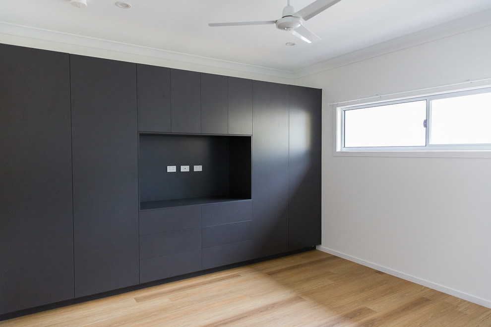 This is an example of a mid-sized contemporary gender-neutral built-in wardrobe in Townsville with flat-panel cabinets, grey cabinets, vinyl floors and brown floor.