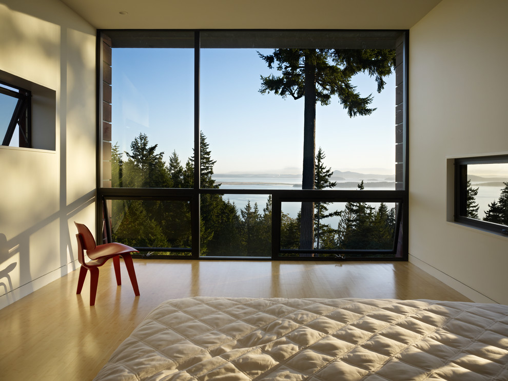 This is an example of a modern bedroom in Seattle with bamboo floors and white walls.