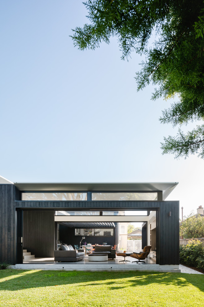 This is an example of a mid-sized contemporary one-storey black house exterior in Sydney with wood siding and a metal roof.