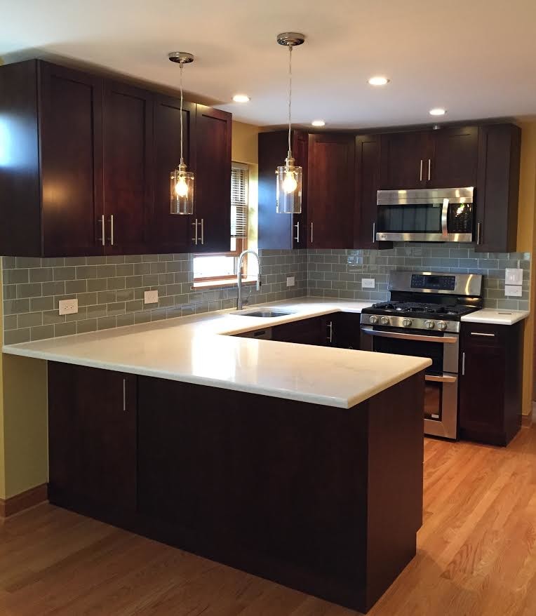 Inspiration for a mid-sized transitional u-shaped medium tone wood floor enclosed kitchen remodel in Chicago with an undermount sink, shaker cabinets, dark wood cabinets, quartzite countertops, gray backsplash, subway tile backsplash, stainless steel appliances and a peninsula