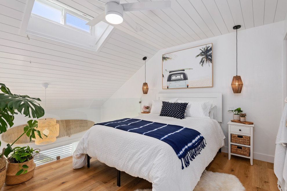Foto di una piccola camera da letto stile loft stile marino con pareti bianche, pavimento in legno massello medio, nessun camino e pavimento marrone