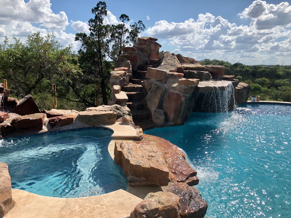 Inspiration for an expansive country backyard custom-shaped natural pool in Austin with a water feature and concrete slab.