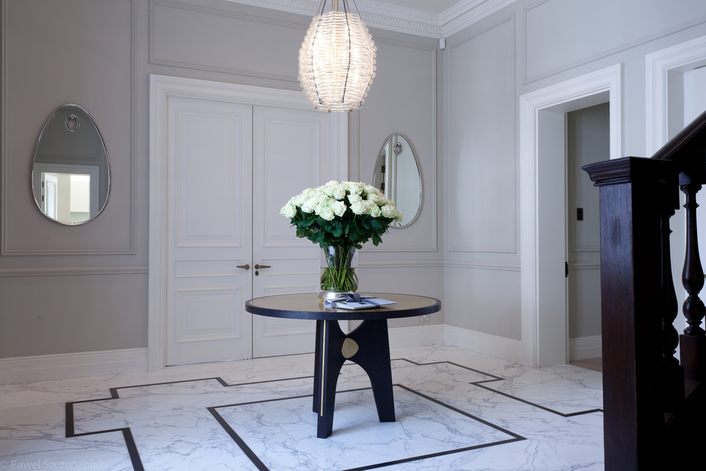 This is an example of a large traditional hallway in London with white walls and marble floors.