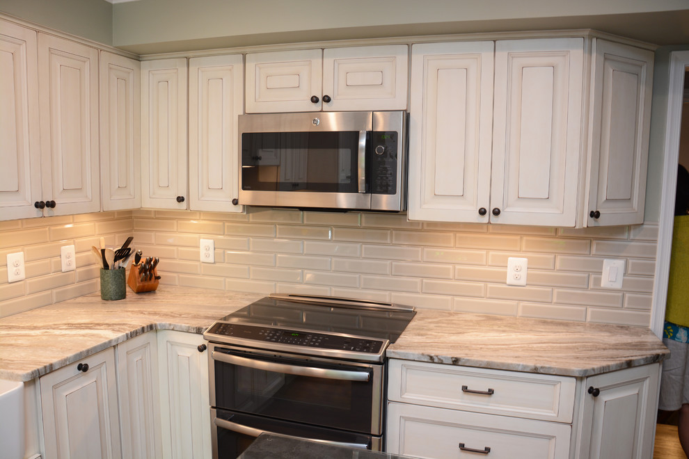 This is an example of a mid-sized traditional l-shaped separate kitchen in DC Metro with a farmhouse sink, raised-panel cabinets, beige cabinets, granite benchtops, beige splashback, mosaic tile splashback, stainless steel appliances, medium hardwood floors, with island, brown floor and beige benchtop.