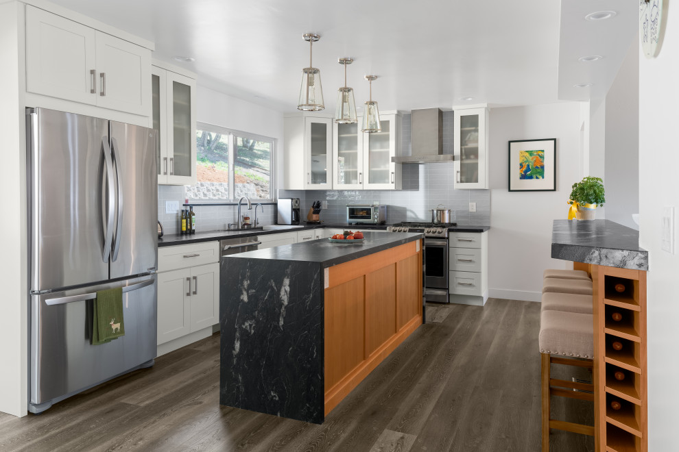 Inspiration for a mid-sized transitional l-shaped vinyl floor and brown floor enclosed kitchen remodel in Other with an undermount sink, shaker cabinets, white cabinets, granite countertops, gray backsplash, ceramic backsplash, stainless steel appliances, an island and black countertops