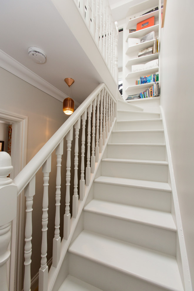 Transitional painted wood straight staircase in London with painted wood risers and wood railing.