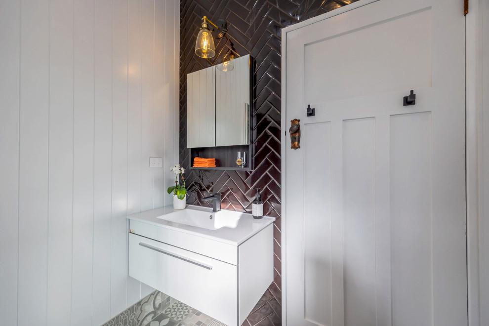 Свежая идея для дизайна: маленькая ванная комната в стиле фьюжн с плоскими фасадами, белыми фасадами, угловым душем, унитазом-моноблоком, черной плиткой, керамической плиткой, серыми стенами, полом из керамогранита, накладной раковиной, столешницей из искусственного камня, серым полом, душем с раздвижными дверями, белой столешницей, тумбой под одну раковину, подвесной тумбой и панелями на части стены для на участке и в саду - отличное фото интерьера