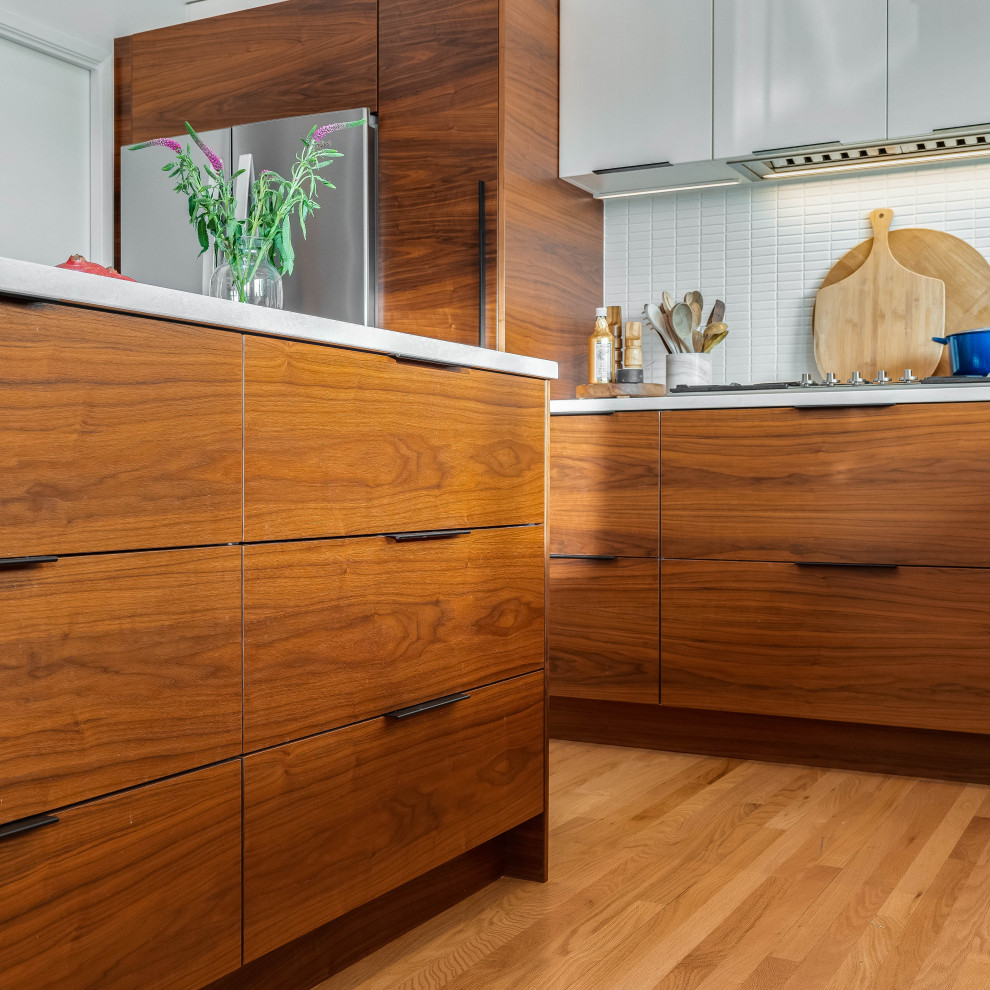 Mid-sized minimalist l-shaped medium tone wood floor, brown floor and vaulted ceiling eat-in kitchen photo in San Luis Obispo with an undermount sink, flat-panel cabinets, medium tone wood cabinets, quartz countertops, white backsplash, ceramic backsplash, stainless steel appliances, an island and white countertops