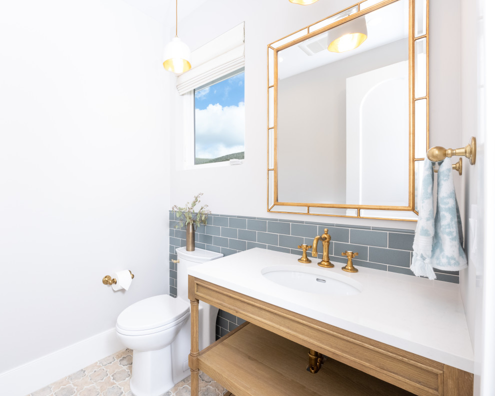 Пример оригинального дизайна: маленькая ванная комната в средиземноморском стиле с фасадами островного типа, светлыми деревянными фасадами, унитазом-моноблоком, синей плиткой, керамической плиткой, бежевыми стенами, полом из цементной плитки, душевой кабиной, врезной раковиной, столешницей из искусственного кварца, бежевым полом, белой столешницей, тумбой под одну раковину и напольной тумбой для на участке и в саду