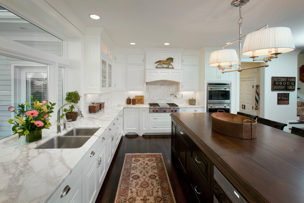 Inspiration for a large traditional kitchen in Cincinnati with an undermount sink, raised-panel cabinets, white cabinets, wood benchtops, white splashback, stainless steel appliances and dark hardwood floors.