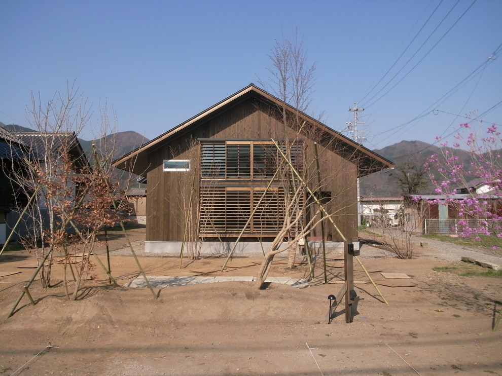 This is an example of a mid-sized asian two-storey house exterior in Other with wood siding, a gable roof and a metal roof.