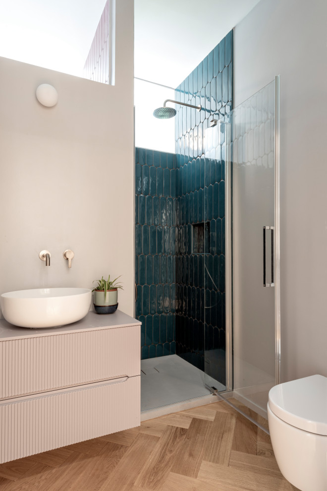 Idéer för att renovera ett litet funkis rosa rosa badrum med dusch, med luckor med upphöjd panel, lila skåp, en dusch i en alkov, en vägghängd toalettstol, grön kakel, porslinskakel, grå väggar, mellanmörkt trägolv, ett fristående handfat, träbänkskiva och dusch med gångjärnsdörr